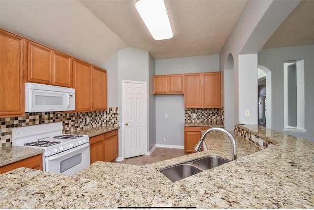 kitchen featuring decorative backsplash, sink, light stone counters, light tile patterned floors, and white appliances