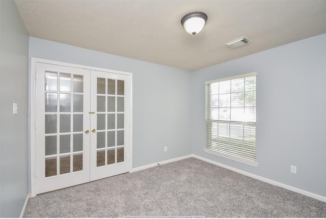 carpeted spare room featuring french doors