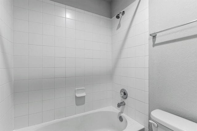 bathroom featuring toilet and tiled shower / bath combo