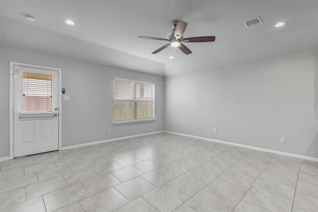 empty room with ceiling fan, light tile patterned floors, and plenty of natural light