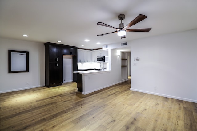 kitchen with light hardwood / wood-style floors, ceiling fan, stove, and kitchen peninsula