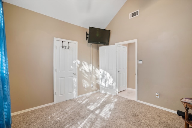 unfurnished bedroom featuring high vaulted ceiling and light colored carpet