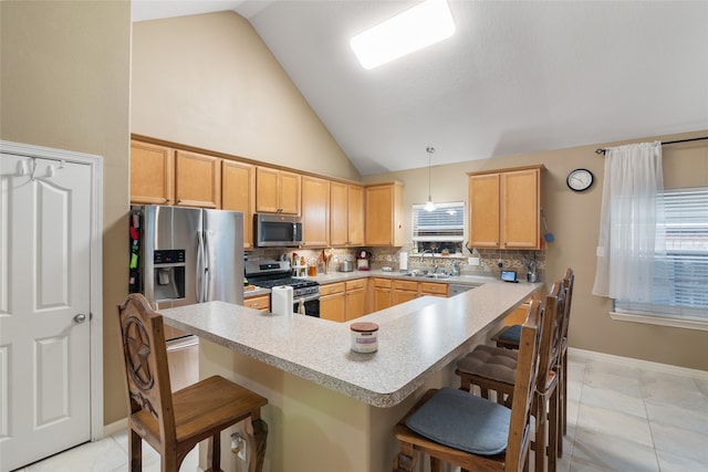 kitchen featuring high vaulted ceiling, kitchen peninsula, a breakfast bar area, pendant lighting, and stainless steel appliances