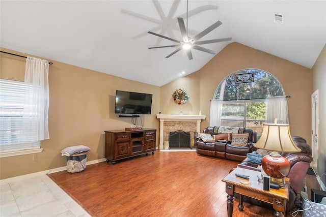 living room featuring ceiling fan, a fireplace, light wood-type flooring, and lofted ceiling