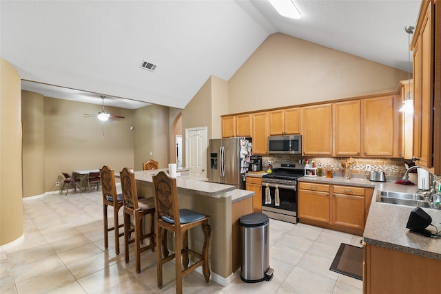 kitchen with ceiling fan, stainless steel appliances, a center island, a breakfast bar area, and decorative backsplash