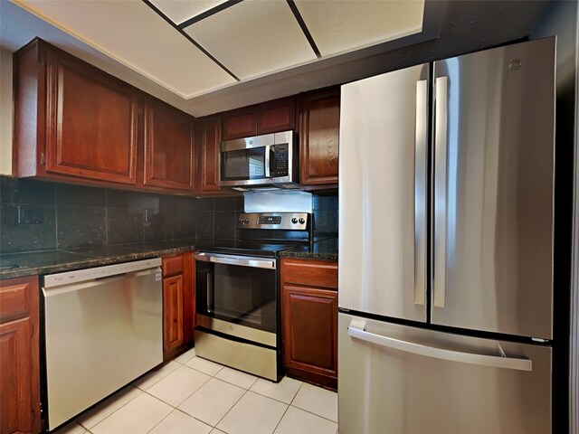 kitchen with stainless steel appliances, light tile patterned floors, and backsplash