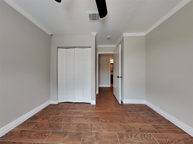 unfurnished bedroom featuring ceiling fan, ornamental molding, a closet, and a textured ceiling