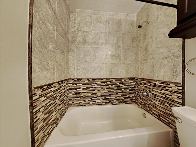 bathroom featuring tiled shower / bath and toilet