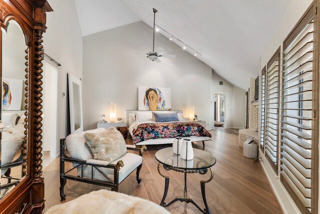 bedroom featuring high vaulted ceiling, light wood-type flooring, and track lighting