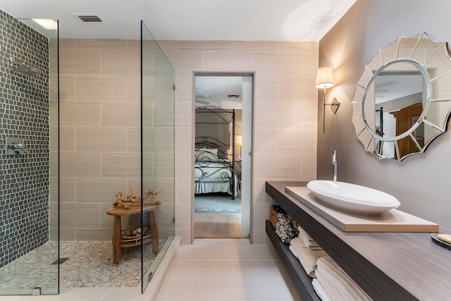 bathroom with tile patterned floors, vanity, a shower with door, and tile walls