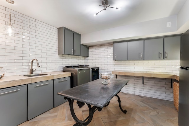 kitchen featuring separate washer and dryer, tasteful backsplash, light parquet floors, gray cabinets, and sink