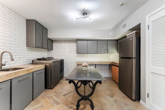 kitchen featuring light parquet floors, tasteful backsplash, stainless steel refrigerator, and sink