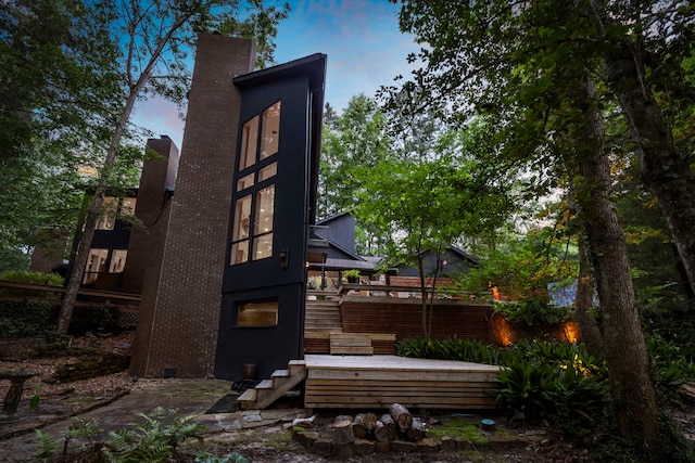 back house at dusk with a wooden deck