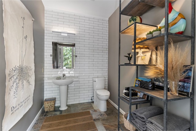 bathroom with brick wall, tile patterned flooring, toilet, and tile walls