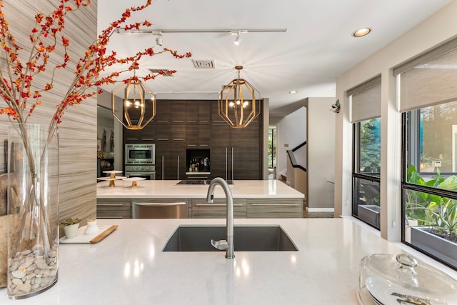 kitchen featuring a notable chandelier, sink, dark brown cabinetry, appliances with stainless steel finishes, and track lighting