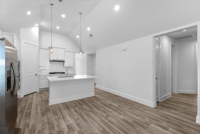 kitchen with white cabinetry, stainless steel refrigerator with ice dispenser, hanging light fixtures, wood-type flooring, and a kitchen island with sink