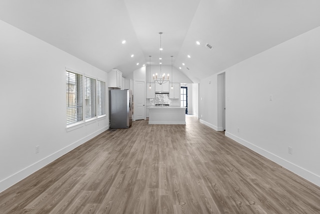 unfurnished living room with light wood-type flooring, lofted ceiling, and an inviting chandelier