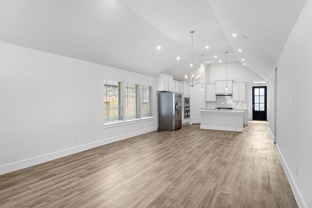 unfurnished living room featuring a chandelier, a healthy amount of sunlight, light hardwood / wood-style flooring, and high vaulted ceiling