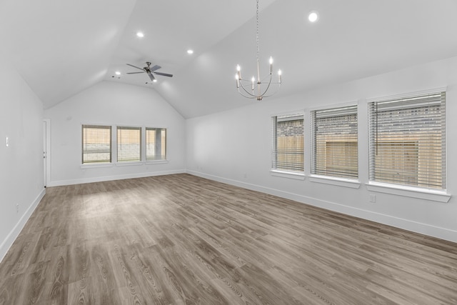 unfurnished living room featuring light wood-type flooring, a wealth of natural light, lofted ceiling, and ceiling fan with notable chandelier