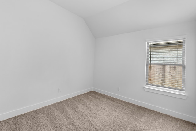 carpeted empty room featuring vaulted ceiling