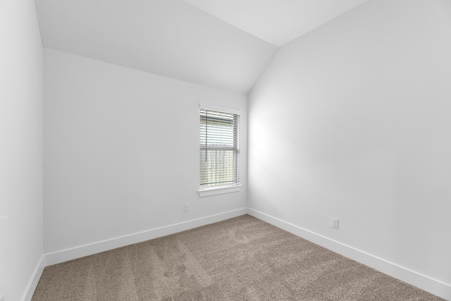 carpeted empty room with lofted ceiling