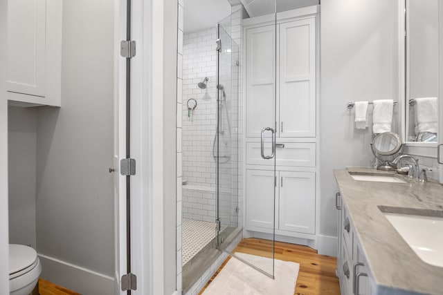 bathroom with a shower with door, toilet, vanity, and hardwood / wood-style floors