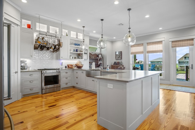 kitchen with tasteful backsplash, high end stove, white cabinetry, light hardwood / wood-style floors, and sink