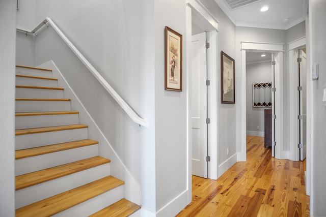 staircase with ornamental molding and hardwood / wood-style flooring