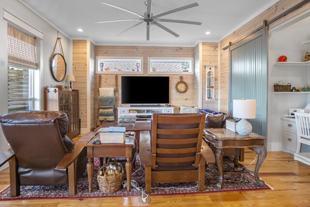 office featuring wooden walls, a barn door, light wood-type flooring, and ceiling fan