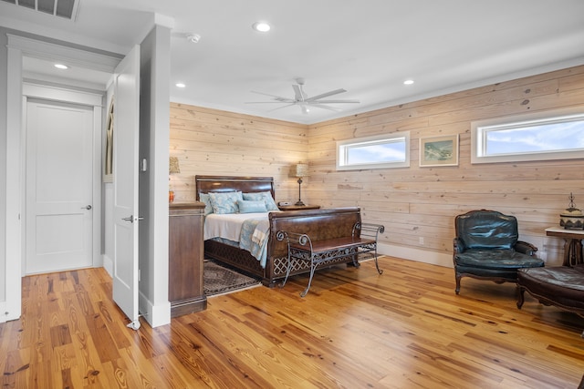 bedroom featuring wooden walls, light wood-type flooring, and ceiling fan