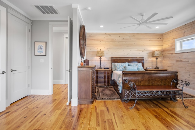 bedroom featuring light hardwood / wood-style flooring, wood walls, and ceiling fan