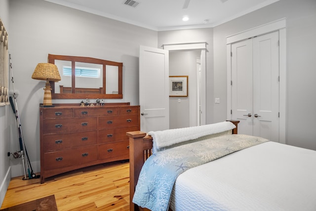 bedroom featuring a closet, crown molding, light wood-type flooring, and ceiling fan