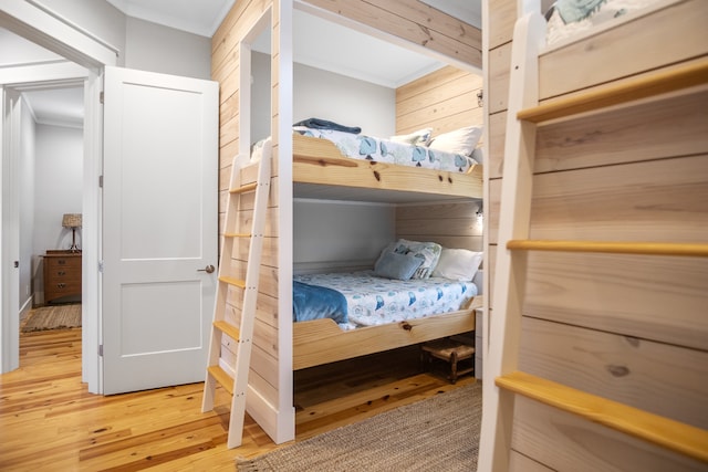 bedroom with crown molding, hardwood / wood-style floors, and wooden walls