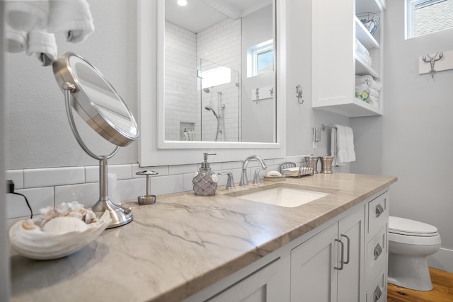 bathroom featuring vanity, toilet, a tile shower, and wood-type flooring