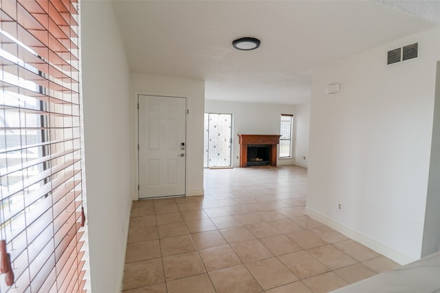 empty room featuring a fireplace and light tile patterned floors