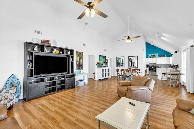 living room with wood-type flooring, high vaulted ceiling, and ceiling fan