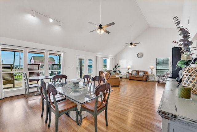 dining room with ceiling fan, rail lighting, high vaulted ceiling, and light wood-type flooring