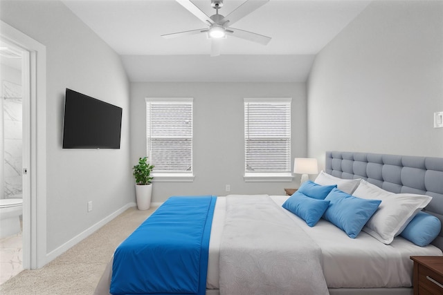 bedroom featuring light carpet, ensuite bath, vaulted ceiling, and ceiling fan