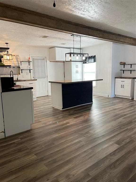 kitchen featuring white cabinetry, a textured ceiling, dark hardwood / wood-style flooring, and beam ceiling