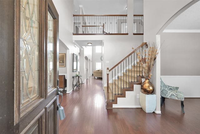 entrance foyer with dark hardwood / wood-style floors, ornamental molding, and a high ceiling