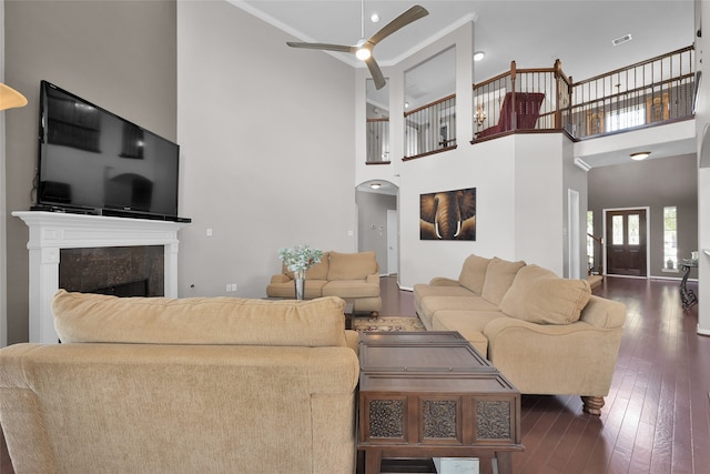 living room featuring ceiling fan, crown molding, dark hardwood / wood-style flooring, and a towering ceiling