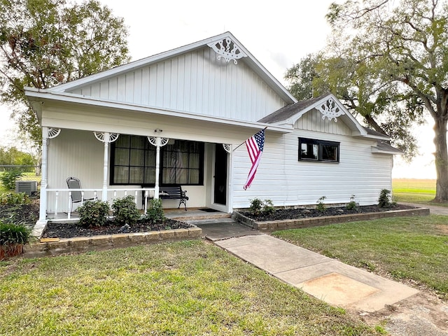 bungalow-style home featuring cooling unit, covered porch, and a front yard