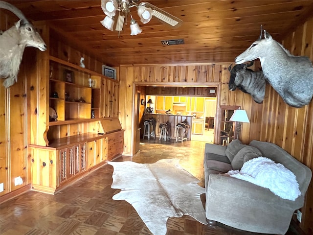 interior space featuring parquet flooring, wooden walls, ceiling fan, and wood ceiling