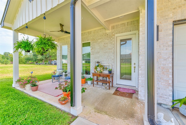 entrance to property with ceiling fan, a lawn, and a garage