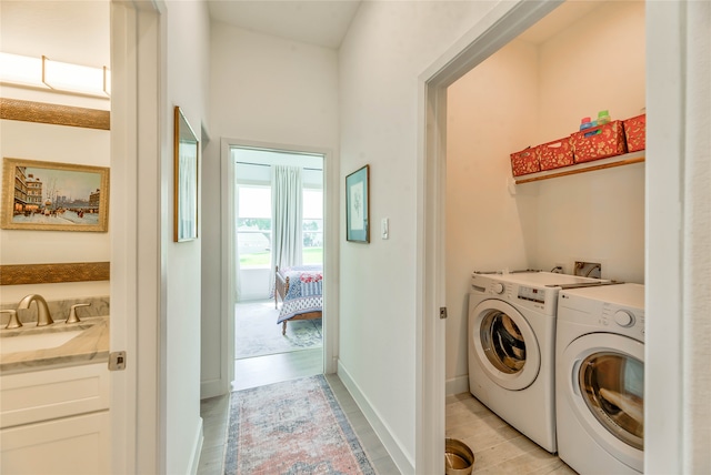 clothes washing area with washing machine and dryer, light wood-type flooring, and sink