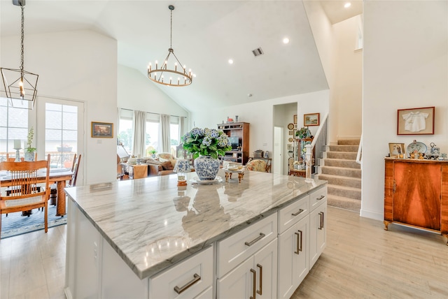 kitchen with light hardwood / wood-style floors, pendant lighting, a kitchen island, high vaulted ceiling, and white cabinetry