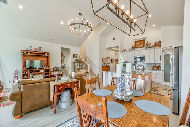 dining area featuring light hardwood / wood-style flooring, a chandelier, and high vaulted ceiling