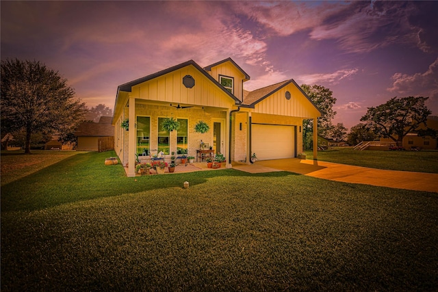 view of front of house with ceiling fan, a garage, and a lawn