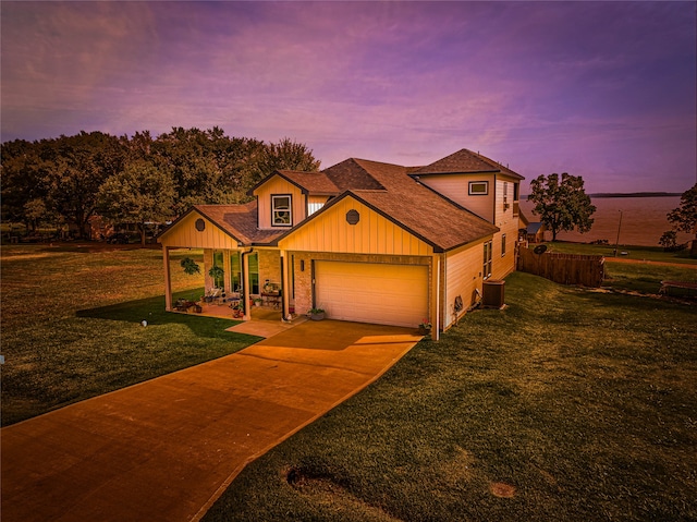 view of front facade featuring a water view, central AC, a lawn, and a garage