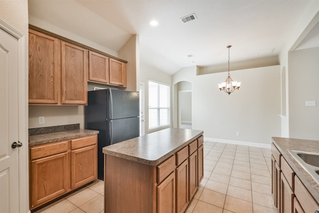 kitchen with hanging light fixtures, black fridge, light tile patterned floors, a center island, and an inviting chandelier